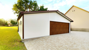9×5,8m-es delux szigetelt mobilgarázs nyeregtetővel, fehér falakkal, sötét diófa szekcionált kapuval és ajtóval, ablakkal, 2db szellőzőráccsal, szegélyekkel, ereszcsatornával, csokoládébarna cserepeslemez tetőborítással