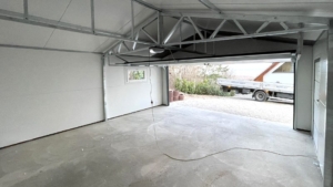 6×5,8m-es delux szigetelt mobilgarázs nyeregtetővel, sötét diófa falakkal, antracitszürke szekcionált kapuval és ajtóval, ablakkal, szellőzőráccsal, szegélyekkel, ereszcsatornával, antracitszürke cserepeslemez tetőborítással