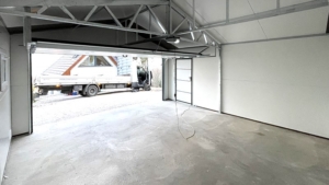 6×5,8m-es delux szigetelt mobilgarázs nyeregtetővel, sötét diófa falakkal, antracitszürke szekcionált kapuval és ajtóval, ablakkal, szellőzőráccsal, szegélyekkel, ereszcsatornával, antracitszürke cserepeslemez tetőborítással