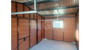 6x3m-es delux fém kerti tároló nyeregtetővel, csokoládébarna cserepeslemez tetővel, világos aranytölgy falakkal, billenőkapuval és ajtóval, ablakkal, ereszcsatornával, szegélyekkel, horganyzott vázszerkezettel, vízszintes lemezborítással