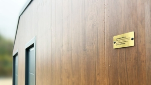 8x6m-es delux szigetelt mobilgarázs, sötét diófa falakkal, nyeregtetővel, antracitszürke szekcionált kapuval és ajtóval, szegélyekkel, ereszcsatonával, horganyzott vázszerkezettel