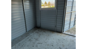 4,8x3,3m-es delux fém kerti tároló hátra lejtő tetővel, antracitszürke színben, ajtóval, 2db ablakkal, ereszcsatornával, szegélyekkel, horganyzott vázszerkezettel, vízszintes lemezborítással