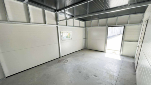 10x6m-es DELUX szigetelt mobilgarázs fordított nyeregtetővel, 2db szekcionált kapuval, 2db ajtóval, ablakkal, 3db szellőzőráccsal, ereszcsatornával, cserepeslemez tetőborítással, horganyzott vázszerkezettel